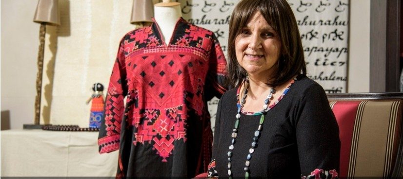 Alia El May Azmeh, fondatrice de Sourires de Femmes, devant une robe brodée traditionnelle